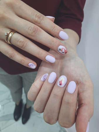 Women's manicure with a delicate purple gel polish and flamingo design. Women's nails covered with pale purple gel polish.の写真素材