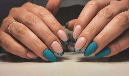 Round nails with a turquoise gel polish and French design. Women's manicure with camouflage gel polish and marine French designの写真素材