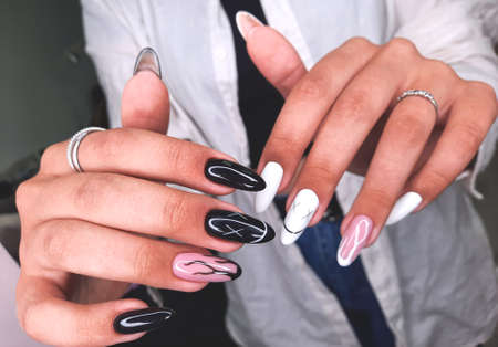Black and white manicure with abstract flame design and marshmallow emoji. Very long nails on women's hands with black and white gel polish. Pink design with black and white flame. smile design.の写真素材