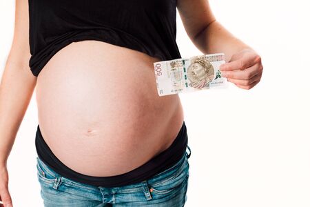 Closeup of pregnant woman belly with her hand holding moneyの写真素材