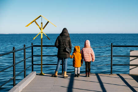 Mom with children looks at the sea from the pierの写真素材