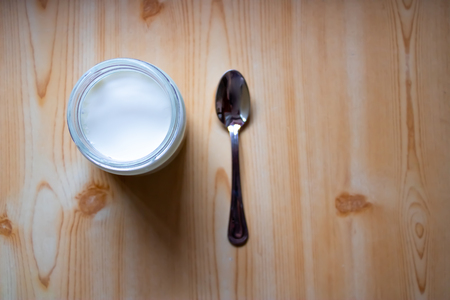 Greek yogurt with the spoon on the wooden background