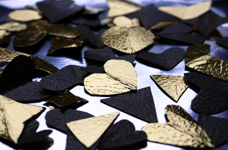 Golden and black hearts made from foil on the blue backgroundの写真素材