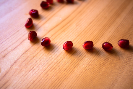 Pomegranate seeds scattered on the wooden table, pomegranate seeds backgroundの写真素材