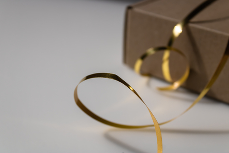 Golden foil ribbon with the closed cupboard giftbox on the background - Imageの写真素材