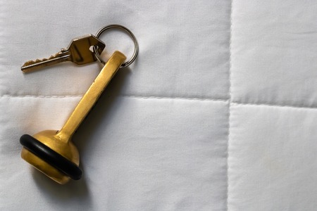 Hotel key laying on the white bed sheets top view - Imageの写真素材