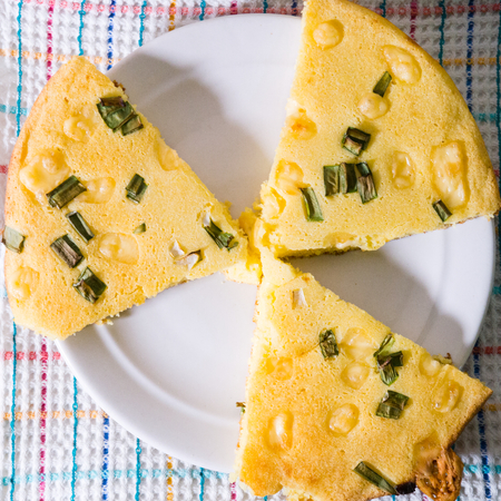 Pizza corn, sliced with green onions, lies on a plate