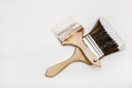 Two paint brushes lie on a white textured surfaceの写真素材