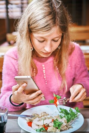 young girl in a cafe with a smartphone. woman having lunchの写真素材