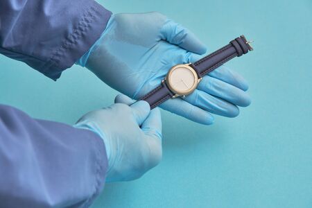 doctor in rubber gloves holds a clock. time care concept
