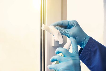 doctor in rubber gloves disinfects window handles with sanitizer and napkins. convalescence