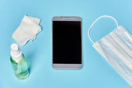 medical mask antiseptic sanitizer and smartphone on blue backgroundの写真素材