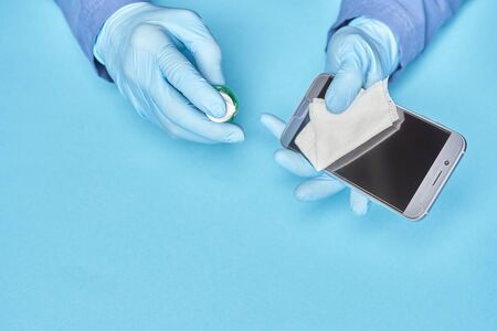 smartphone disinfection. a man wipes a phone screen with a sanitizer