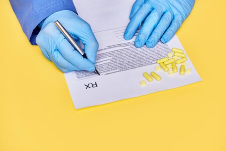 doctor prescribes rx on pills. yellow backgroundの写真素材