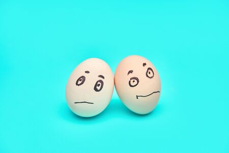 eggs with a sad face hugging each other. aqua backgroundの写真素材