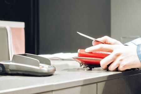 the girl is paying with credit card for purchase at the checkout with bank terminal woman is holding...