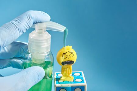 hand in a medical glove washes a toy person in a medical face mask with a sanitizer. creative...
