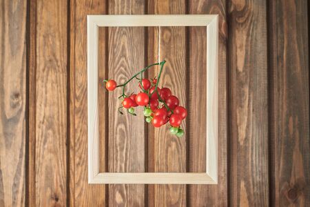 red cherry tomatoes in a frame on a wooden wall. still life conceptの写真素材