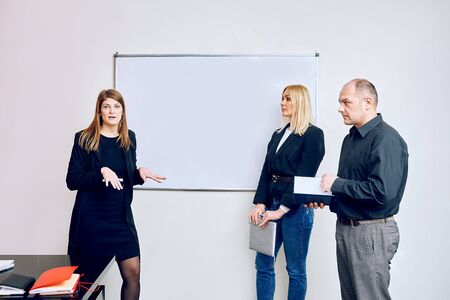 team in the office is working. managers have a discussion near the board.の写真素材