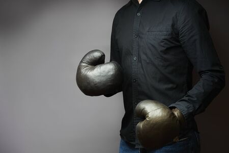 man in a black shirt in old leather boxing gloves is ready for battle. concept businessの写真素材