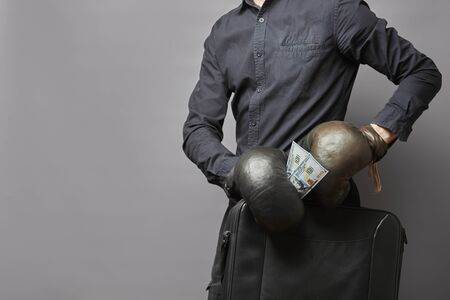 man in a shirt and leather boxing gloves holds a briefcase with money. business protection concept