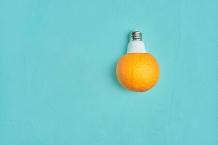 orange in a light bulb on a turquoise background. creative design concept