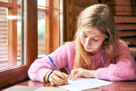 young girl signs a document. student learns to write an abstract