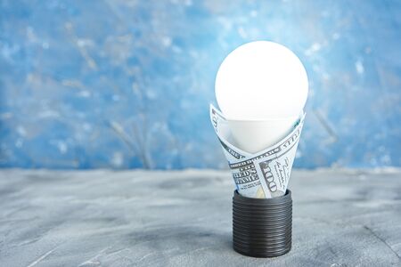 luminous led lamp in an electric socket in a 100 dollar bill. electrical energy conservation conceptの写真素材