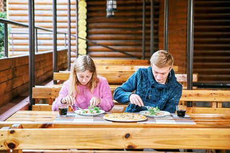 young couple eating salad and pizza together at a cafe aloneの写真素材