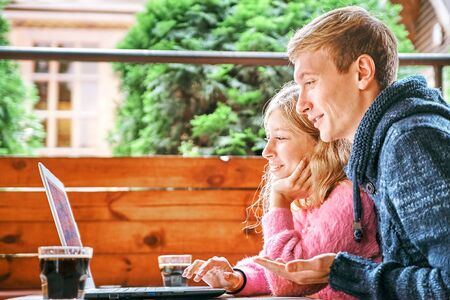 man and a girl watching a laptop together in a cafe