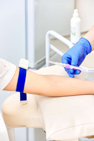 woman gives blood. doctor holds a syringe in his hands