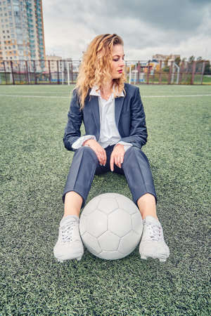 portrait of a beautiful woman football player in a strict office suit, concept sports office manager leisureの写真素材