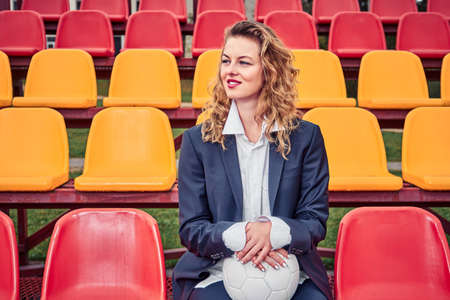 portrait of a beautiful woman soccer cheerleader in the stands of a stadium with a ballの写真素材