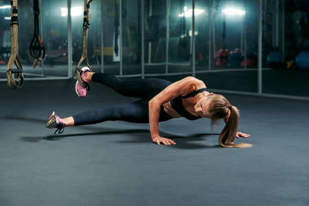 athletic woman doing acrobatic exercise on trx workout