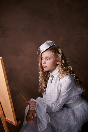 vintage portrait of artist girl. child in white dress paints pictureの写真素材