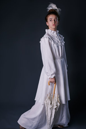 stylish retro portrait of a teenage girl in a white dress. studio. dark background