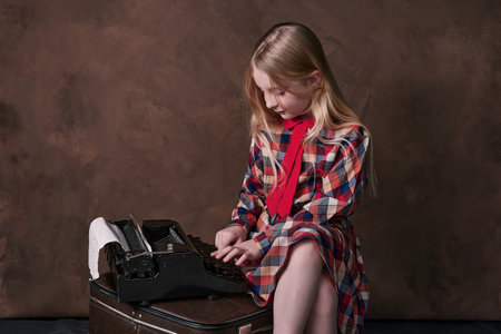 little girl is typing text on typewriter. retro styleの写真素材