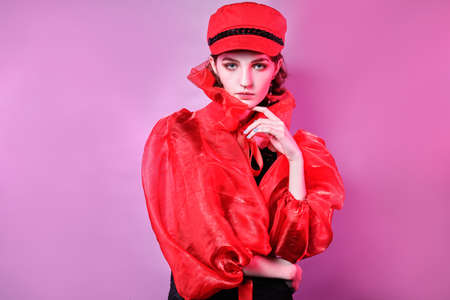 portrait of fashionable young girl in red hat. pink background