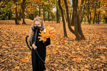 little girl with white rose in the hands of hay. child in gas mask with breathing apparatus backpack...