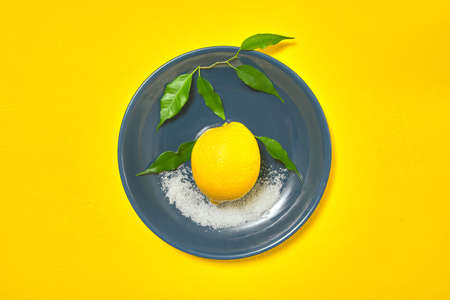 whole yellow lemon on blue plate with sugarの写真素材