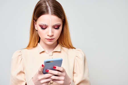 young girl looks into smartphone. gray backgroundの写真素材