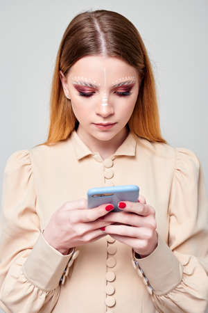 young girl looks into smartphone. gray backgroundの写真素材