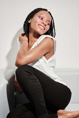 beautiful african american girl with bright pink makeup sits on the sofa