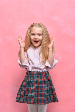 surprised little girl. emotion delight. schoolgirl in uniform. pink backgroundの写真素材