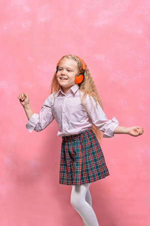 little girl in headphones is dancing. pink backgroundの写真素材