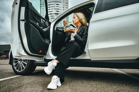 business lunch in the car. girl eating fast food on the road