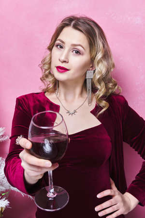 woman in burgundy dress stretches out her hand with a glass of wineの写真素材