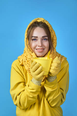 woman in yellow clothes drinks tea. blue backgroundの写真素材