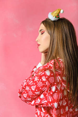 profile portrait of a beautiful girl in New Year's pajamas. pink background