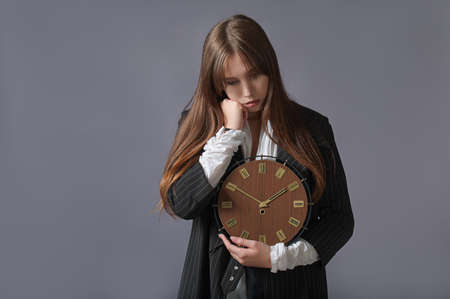creative portrait of a business woman with a large clock in her hands. concept time is running outの写真素材